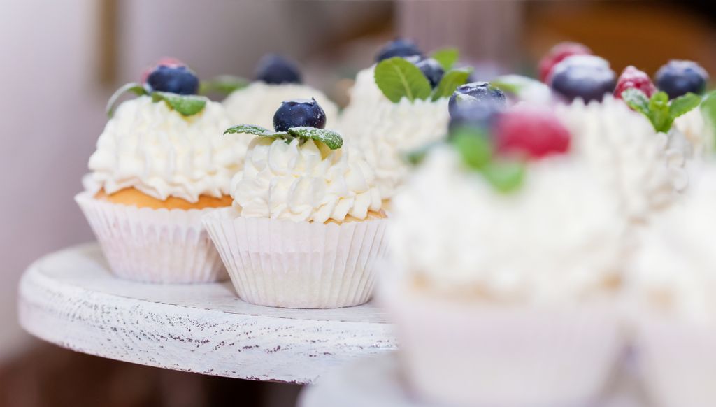 Close-up of cupcakes topped with blueberries, raspberries, and creamy frosting, ideal for dessert and baking themes.